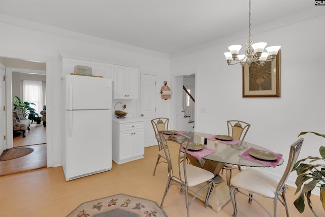 dining room featuring crown molding, an inviting chandelier, and light wood-type flooring