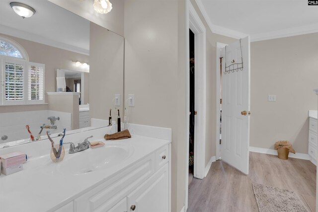 bathroom with crown molding, hardwood / wood-style floors, vanity, and a tub to relax in