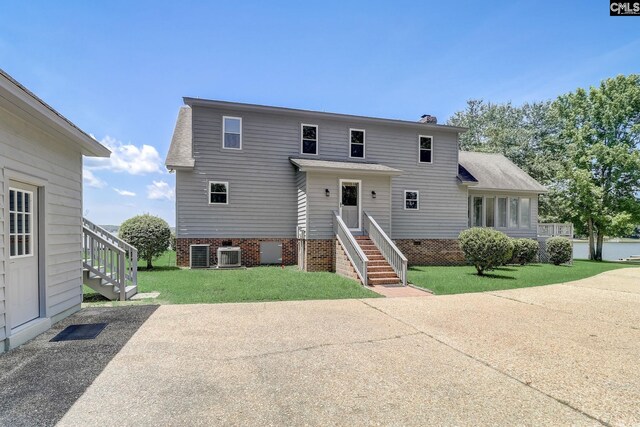 view of front of home with a shingled roof, a chimney, a front lawn, and central air condition unit