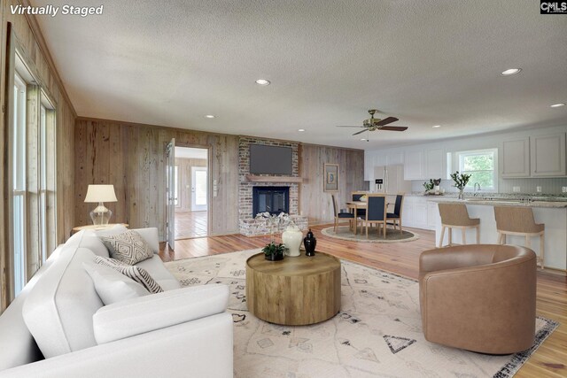 living area featuring light wood-style flooring, a fireplace, a textured ceiling, and recessed lighting