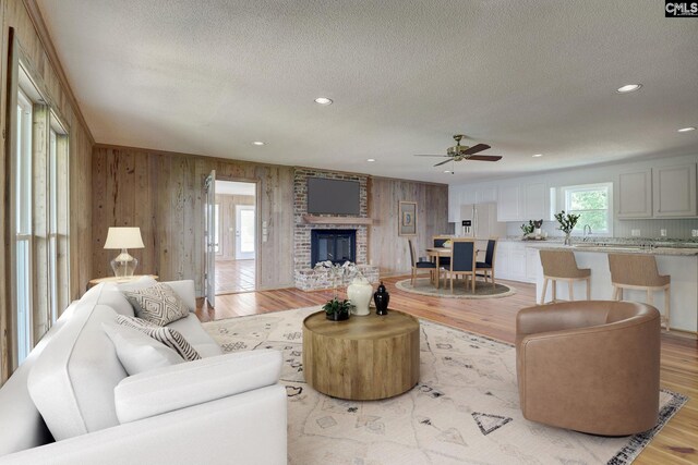 living room with a textured ceiling, recessed lighting, light wood-type flooring, and a brick fireplace