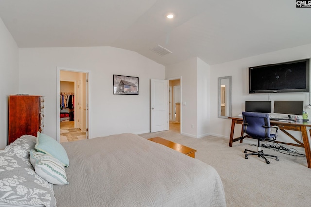 carpeted bedroom with vaulted ceiling and a walk in closet