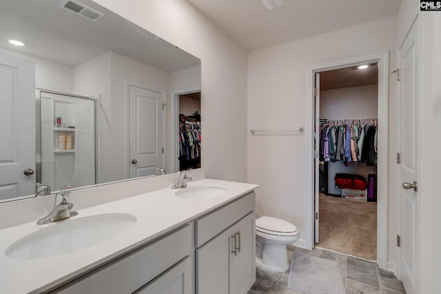 bathroom featuring vanity, a shower with door, and toilet