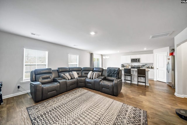 living room with hardwood / wood-style floors, a wealth of natural light, and a notable chandelier