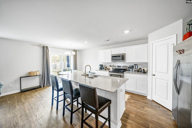 kitchen with stainless steel appliances, white cabinetry, a breakfast bar, and a center island with sink