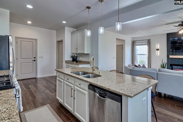 kitchen with sink, decorative light fixtures, stainless steel appliances, a kitchen island with sink, and white cabinets