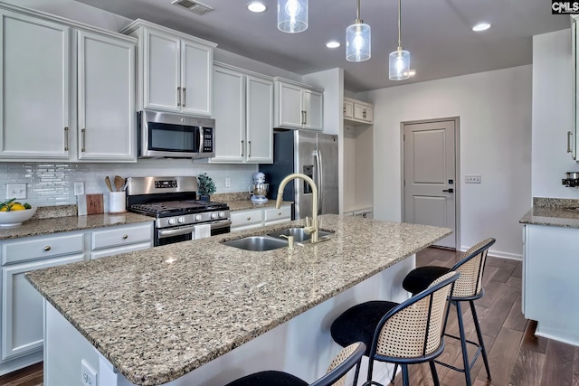 kitchen featuring white cabinets, appliances with stainless steel finishes, sink, and a kitchen island with sink