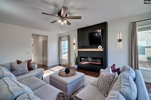 living room with a large fireplace, hardwood / wood-style floors, and ceiling fan