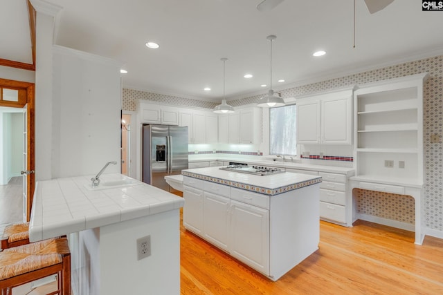 kitchen featuring stainless steel appliances, sink, pendant lighting, and white cabinets