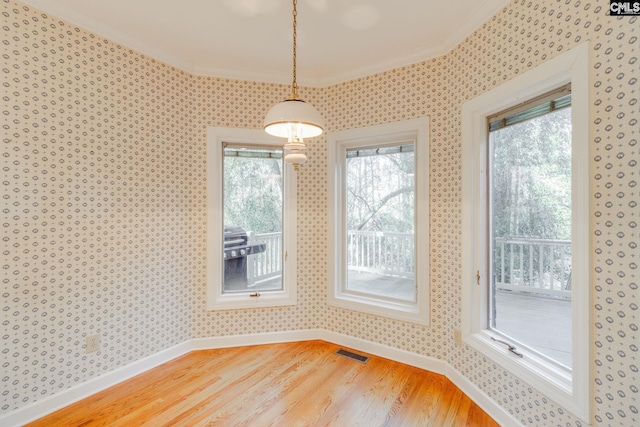 unfurnished dining area with ornamental molding, a healthy amount of sunlight, and hardwood / wood-style floors