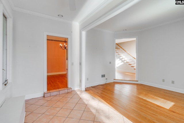 empty room featuring ornamental molding, a notable chandelier, and light wood-type flooring