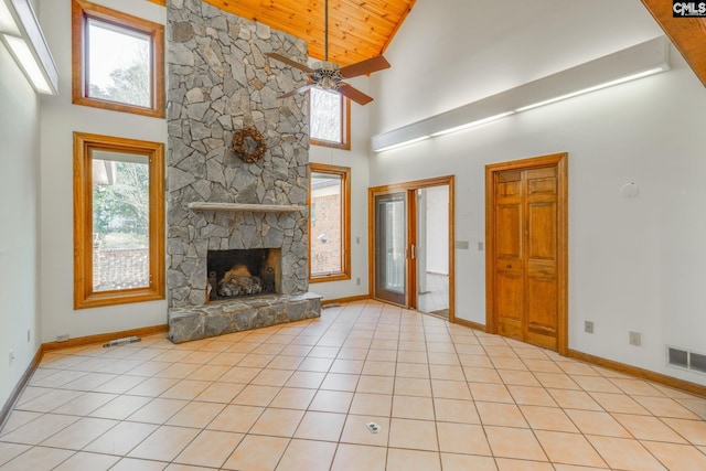 unfurnished living room featuring light tile patterned flooring, wooden ceiling, a stone fireplace, and a wealth of natural light