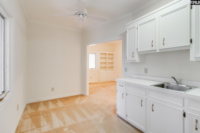 kitchen with sink, crown molding, ceiling fan, light colored carpet, and white cabinets