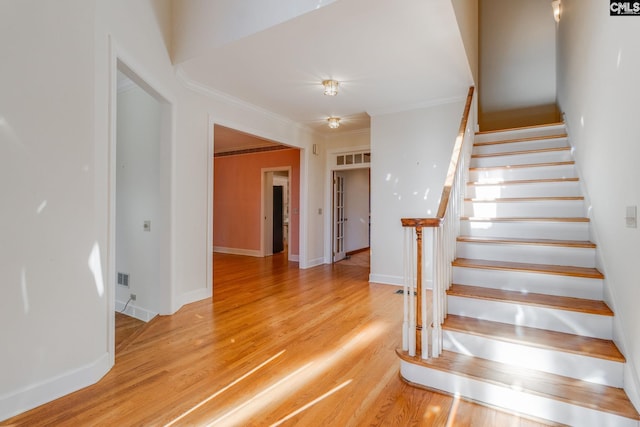 stairway with wood-type flooring and ornamental molding