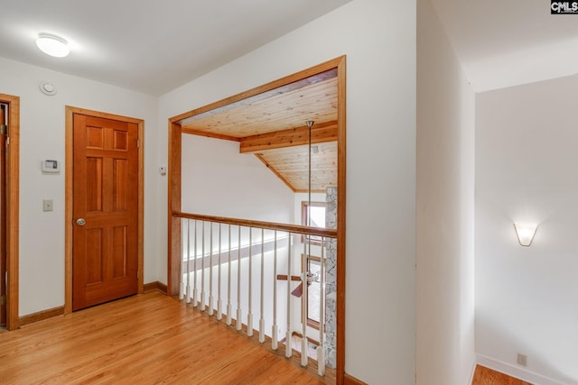 hall with beamed ceiling, wooden ceiling, and light wood-type flooring