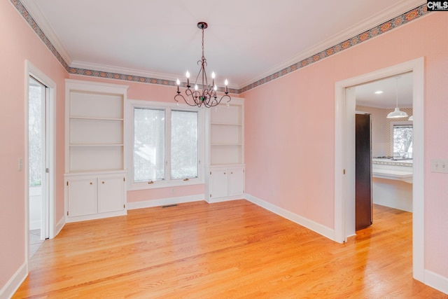 unfurnished dining area with ornamental molding, a notable chandelier, and light wood-type flooring