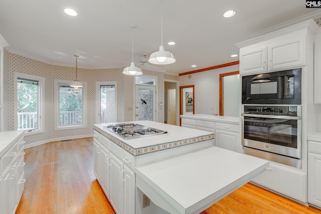 kitchen with appliances with stainless steel finishes, a center island, hanging light fixtures, and white cabinets