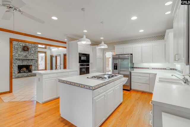 kitchen with a kitchen island, decorative light fixtures, white cabinetry, sink, and stainless steel appliances