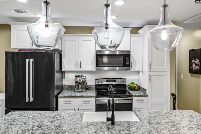 kitchen with light stone counters, stainless steel appliances, and white cabinets