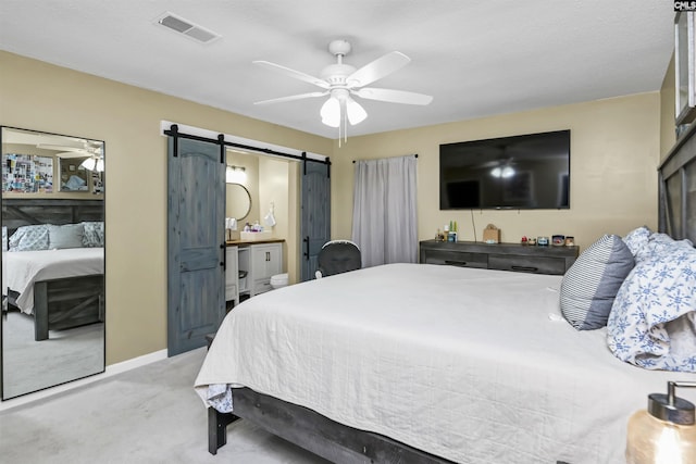 carpeted bedroom with connected bathroom, a barn door, and ceiling fan