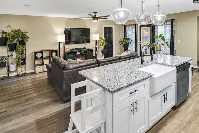 kitchen with sink, white cabinetry, wood-type flooring, dishwasher, and pendant lighting