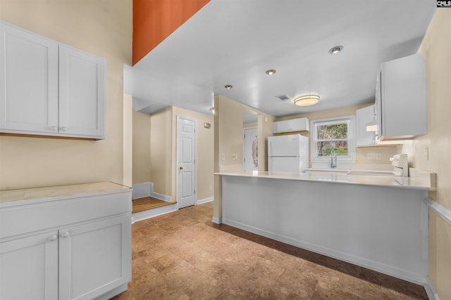 kitchen with range, sink, white cabinets, and white fridge