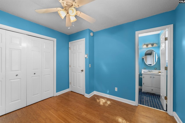 unfurnished bedroom with ceiling fan, ensuite bath, light hardwood / wood-style floors, and a closet