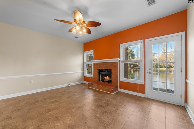 unfurnished living room with a brick fireplace and ceiling fan