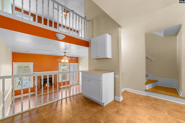 living room featuring a towering ceiling, ceiling fan, and light tile patterned flooring