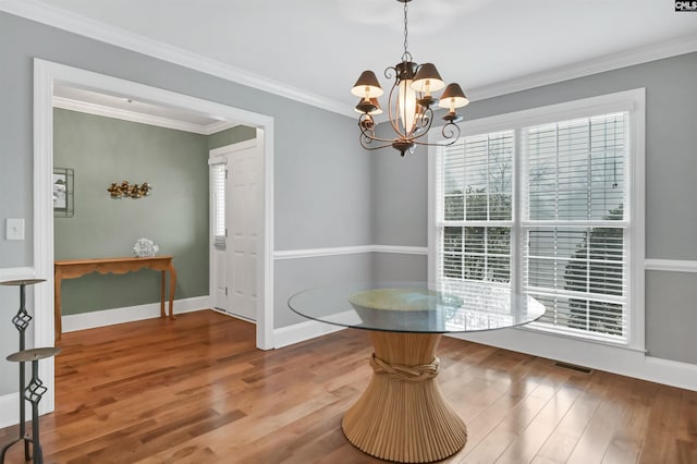 unfurnished dining area with crown molding, an inviting chandelier, and hardwood / wood-style floors