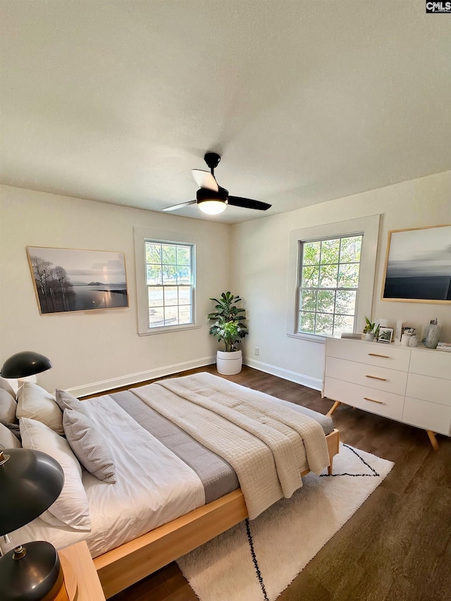 bedroom with multiple windows, dark wood-type flooring, and ceiling fan