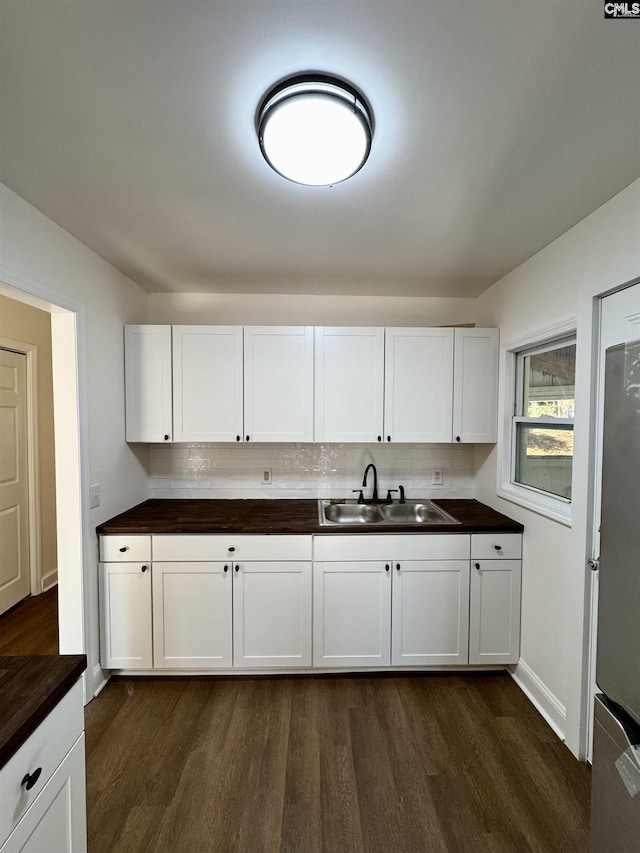 kitchen with sink, dark wood-type flooring, stainless steel fridge, and white cabinets