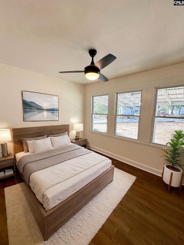 bedroom featuring dark wood-type flooring, ceiling fan, and multiple windows