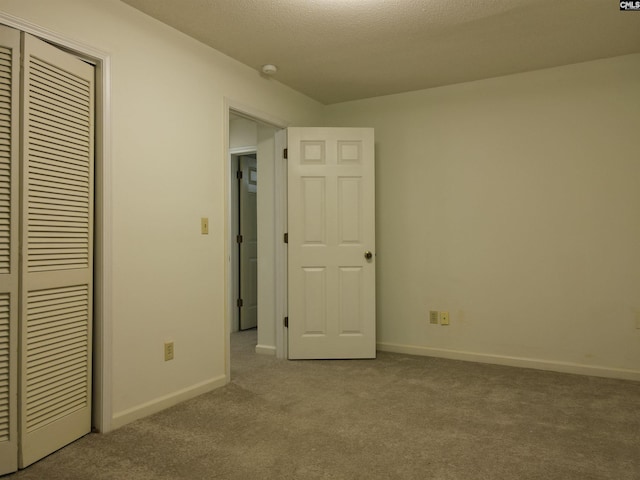 unfurnished bedroom featuring light carpet, a textured ceiling, and a closet