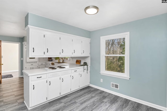 kitchen featuring white electric cooktop, sink, white cabinets, and light hardwood / wood-style flooring