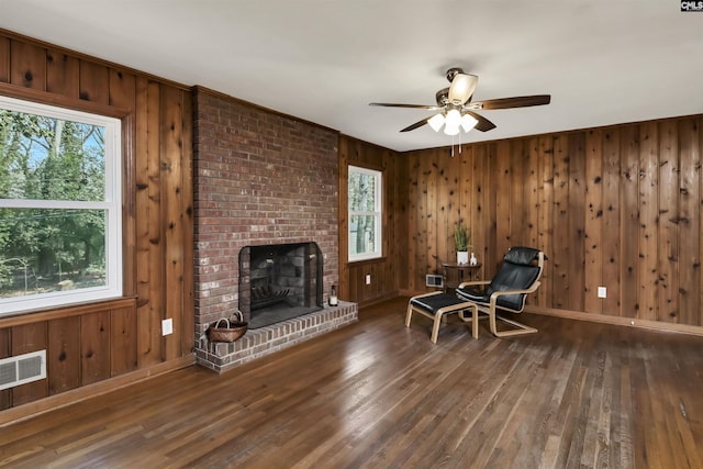 unfurnished room with dark wood-type flooring, a fireplace, wooden walls, and ceiling fan