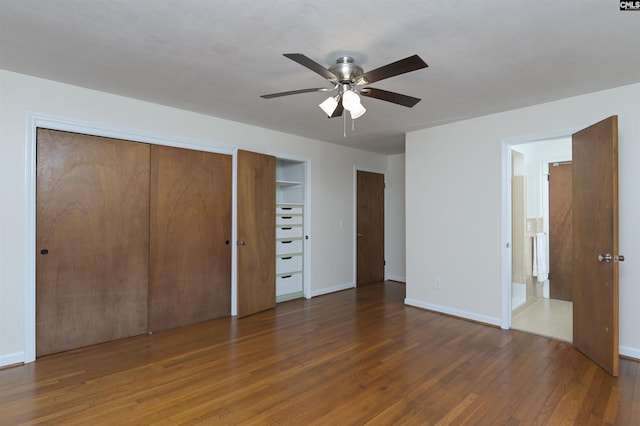 unfurnished bedroom with ceiling fan, dark hardwood / wood-style flooring, and two closets