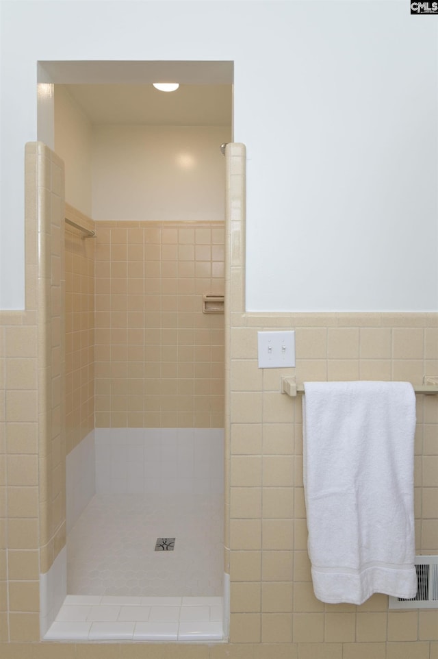 bathroom with tiled shower and tile walls