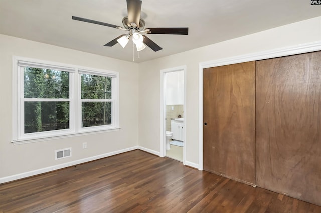 unfurnished bedroom with dark wood-type flooring, connected bathroom, ceiling fan, and a closet