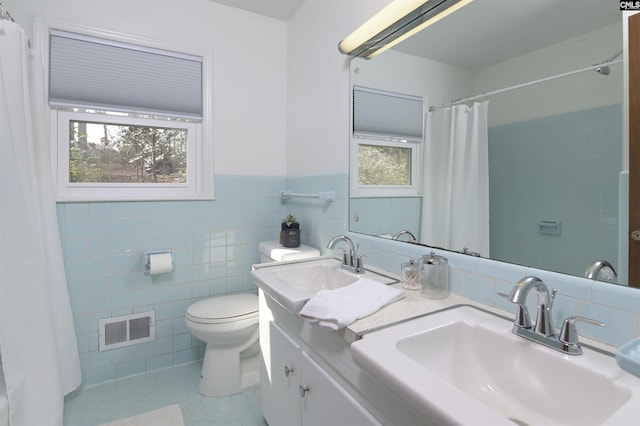 bathroom with vanity, toilet, tile patterned flooring, and tile walls