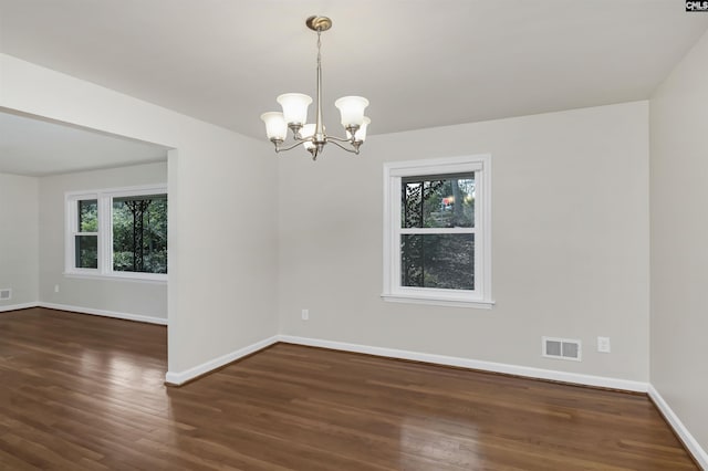 empty room with dark hardwood / wood-style floors and a notable chandelier