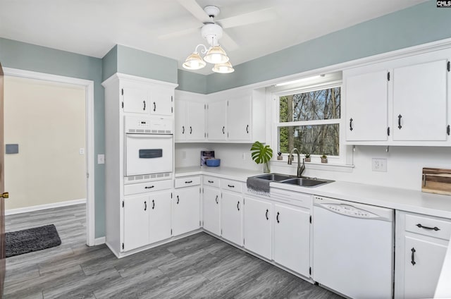 kitchen with sink, white appliances, light hardwood / wood-style flooring, white cabinets, and decorative light fixtures