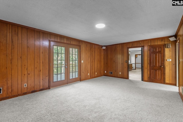 carpeted spare room with french doors, crown molding, and a textured ceiling