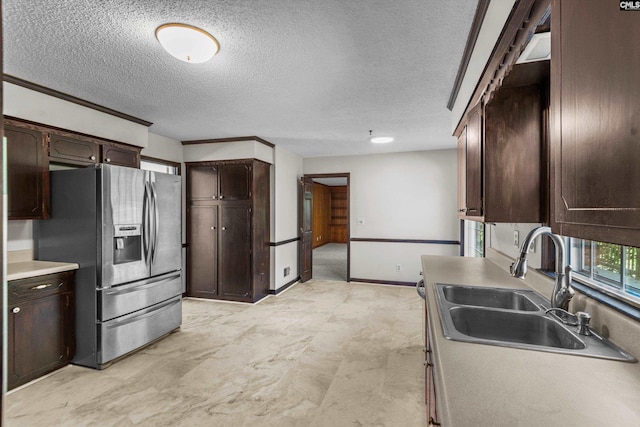 kitchen featuring stainless steel fridge, sink, dark brown cabinets, and a textured ceiling