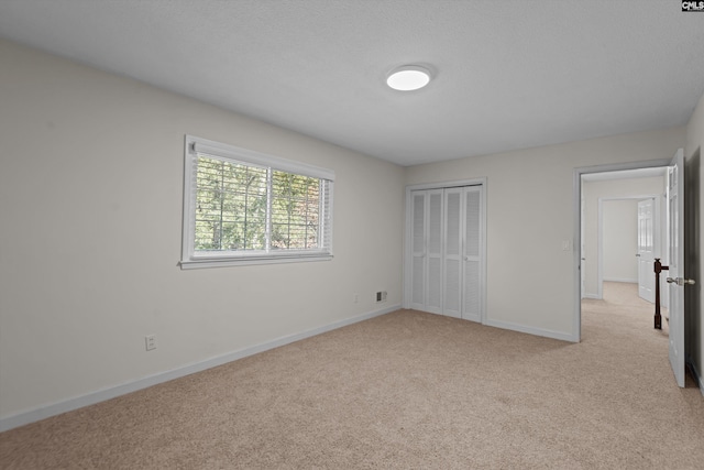 unfurnished bedroom featuring light carpet and a closet