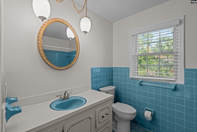 bathroom featuring vanity, tile walls, and toilet