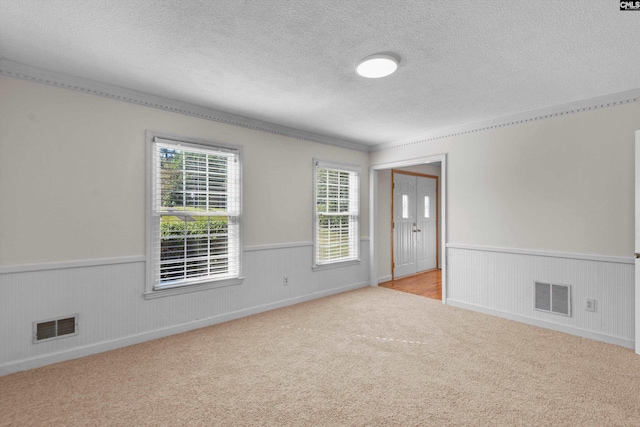 carpeted spare room with ornamental molding and a textured ceiling