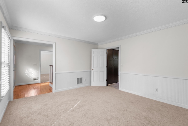 unfurnished room with crown molding, carpet flooring, a wealth of natural light, and a textured ceiling