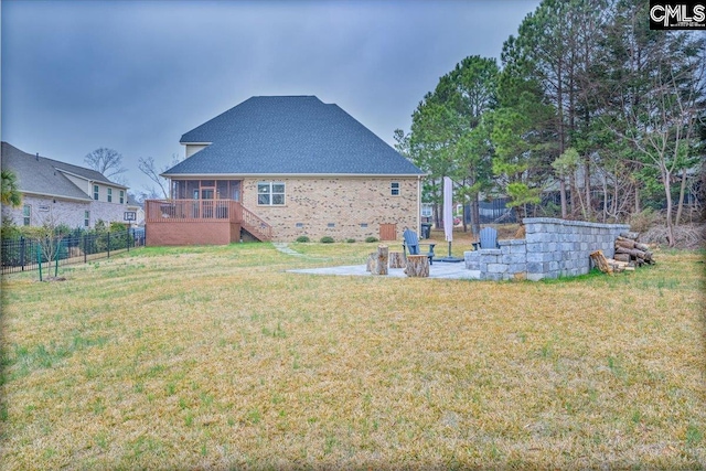 back of property with a lawn, a patio area, and a fire pit