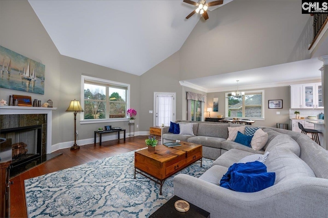 living room with a tiled fireplace, ceiling fan with notable chandelier, dark hardwood / wood-style flooring, and high vaulted ceiling